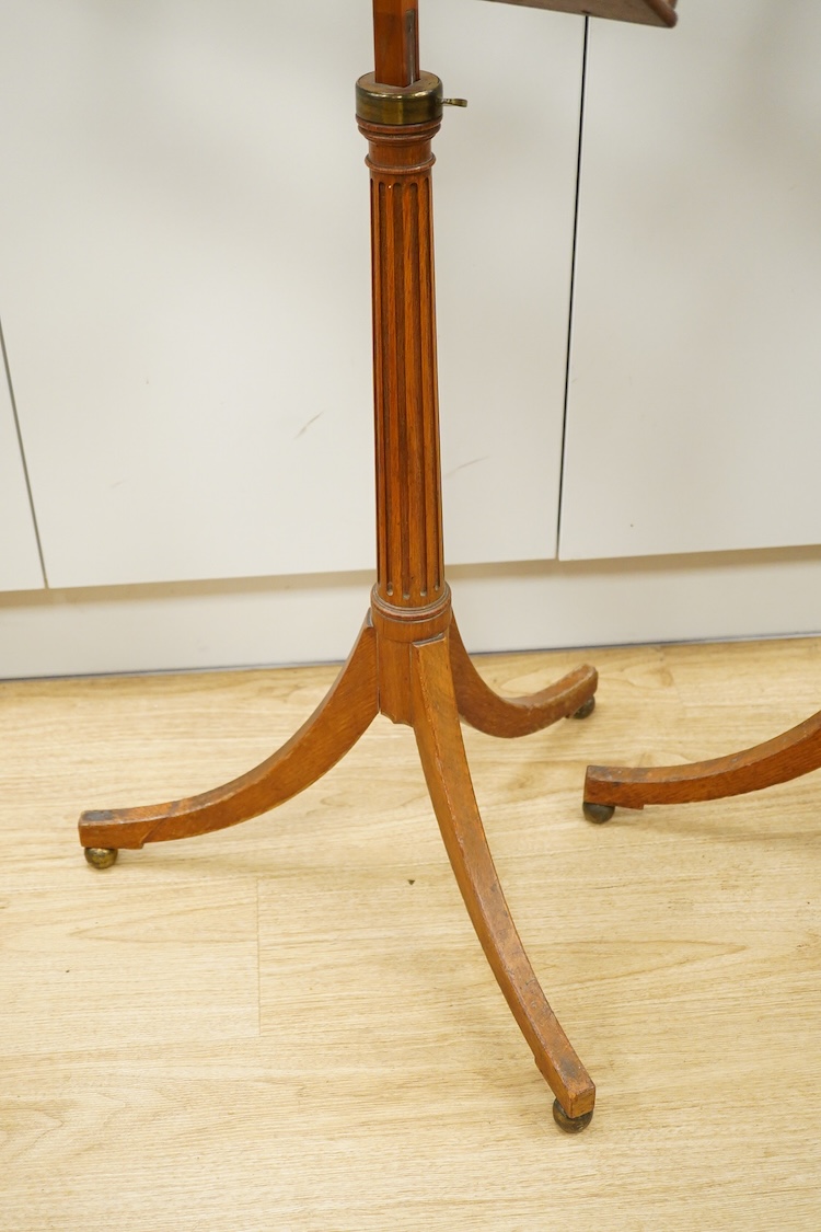 A set of three early 20th century oak music stands, all with fluted pedestal supports and tripod legs with brass feet, adjustable height music desks, maximum overall height when extended 137cm, the angle of the desks is